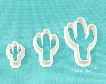 Peut inclure: Trois emportes-pièces en plastique blanc en forme de cactus de différentes tailles. Le plus grand emporte-pièce mesure environ 15 cm de haut, le moyen environ 10 cm et le plus petit environ 5 cm.