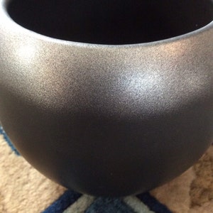 May include: A large, round, silver planter with a textured surface. The planter is made of a durable material and is perfect for indoor or outdoor use.