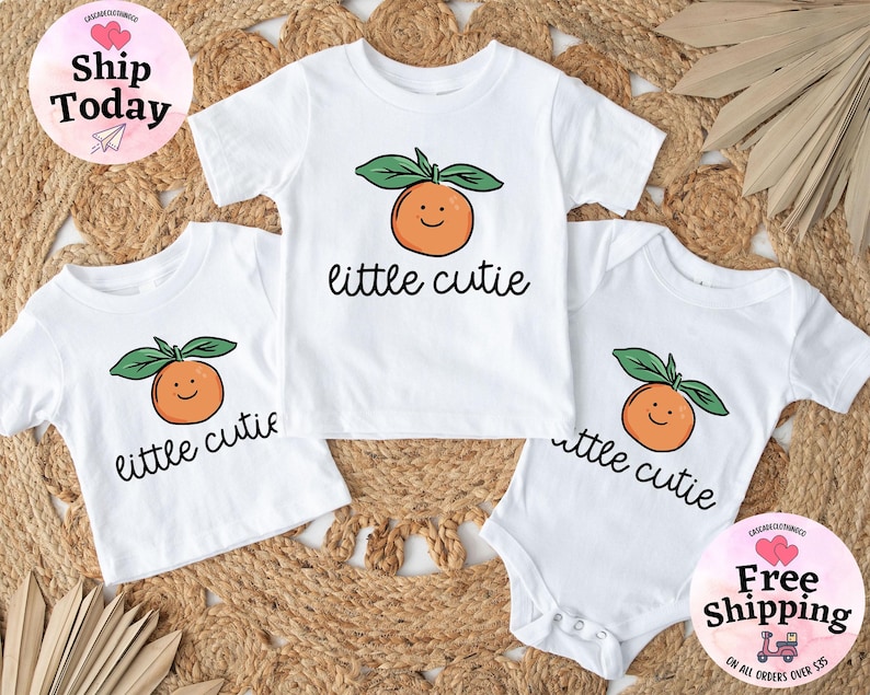 May include: Three white t-shirts with a cute orange graphic and the text "little cutie" printed on them.