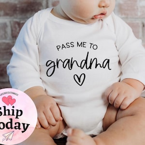May include: White long-sleeve baby onesie with black text that reads "Pass me to grandma" with a small heart.