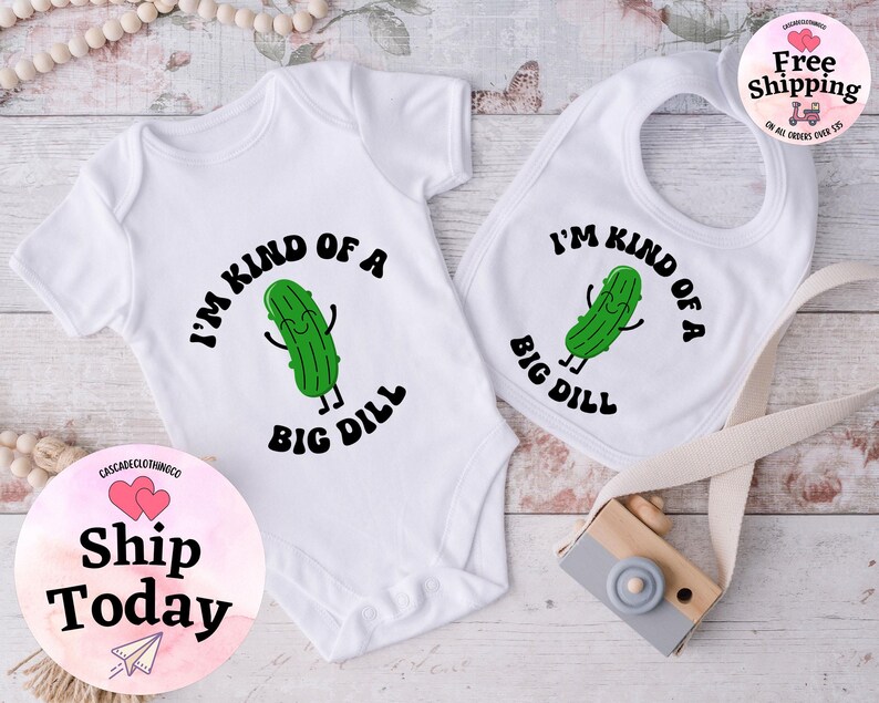 May include: A white baby bodysuit and bib with a green pickle cartoon character and the text "I'm kind of a big dill".