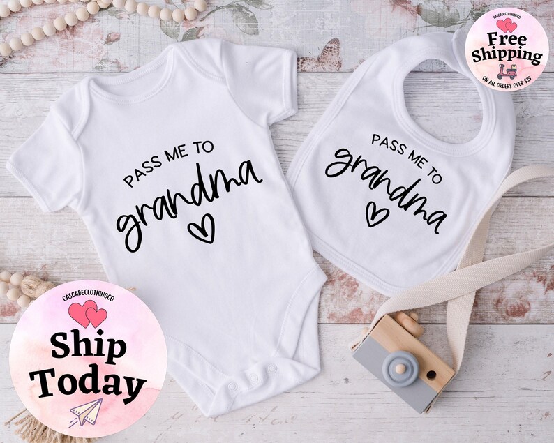 May include: White baby bodysuit and bib with black text that reads "Pass me to grandma" with a heart symbol.