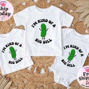 May include: Three white t-shirts with a green pickle graphic and the text "I'm kind of a big dill".