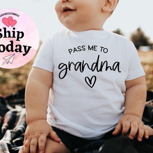 May include: White baby onesie with black text that reads "Pass me to grandma" with a small heart underneath.