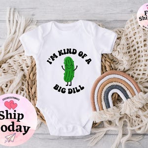 May include: White baby onesie with a green cartoon pickle and the text "I'm kind of a big dill".