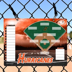 May include: A baseball lineup board featuring a baseball field diagram in green and brown, with the word "HURRICANES" in orange. The board includes space for lineup and substitutions, with a stormy orange background.