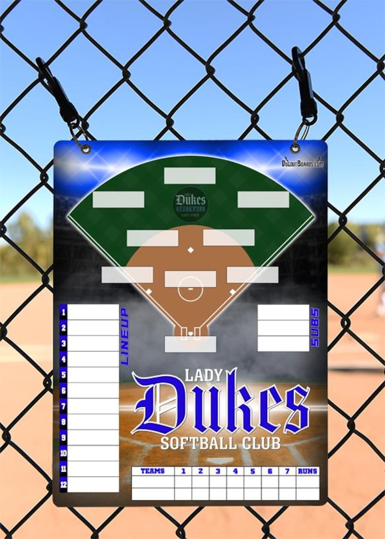 May include: A rectangular softball lineup board with a baseball field diagram, the words "Lady Dukes Softball Club," and a space for team lineups. The board is blue, green, and brown, with a chain-link fence in the background.