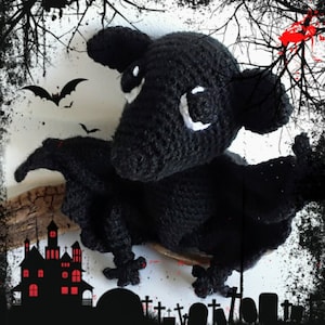 May include: Black crocheted bat plush toy with white eyes. The bat is sitting on a branch with a spooky Halloween background.