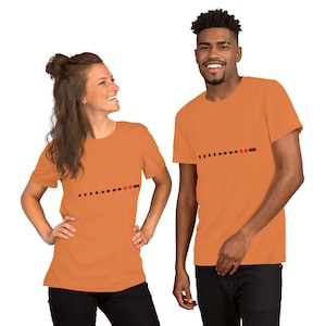 May include: Two people wearing orange t-shirts. Each shirt has a black arrow design with a red circle and the word "studio" in black. The shirts are short-sleeved.