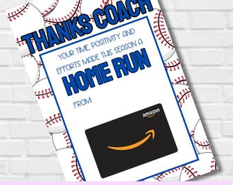 May include: A baseball-themed gift card holder with the words "THANKS COACH" in blue. The card reads "YOUR TIME, POSITIVITY AND EFFORTS MADE THIS SEASON A HOME RUN." An Amazon gift card is included. The background features baseballs.