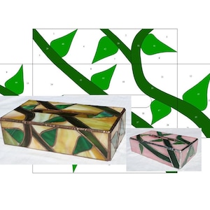 Puede incluir: Dos cubiertas de caja de pañuelos de vidrio tintado. Una es verde y marrón con un patrón de vid. La otra es rosa y verde con un patrón de vid.