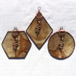 May include: Three decorative glass ornaments with copper frames and snake charms. Each ornament features a different pattern of brown and beige.