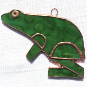 May include: A green stained glass frog ornament with copper accents. The frog is in a leaping pose with its legs outstretched.