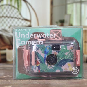 May include: A clear plastic package containing a SunnyLife Underwater Camera. The camera has a pink and teal tropical design with a parrot and leaf pattern. The text "Underwater Camera" is printed on the package.