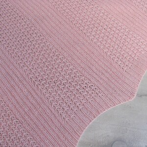 May include: A pink crocheted shawl with a delicate openwork pattern. The shawl is made with a soft yarn and has a scalloped edge.