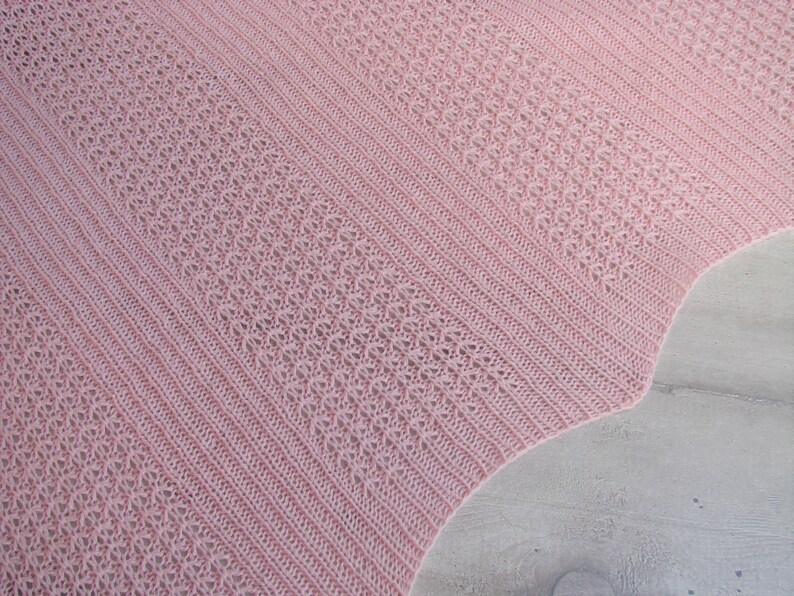 May include: A pink crocheted shawl with a delicate openwork pattern. The shawl is made with a soft yarn and has a scalloped edge.