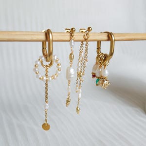composizione di piercing all'orecchio, orecchini in acciaio, perle d'acqua dolce, gioielli fatti a mano