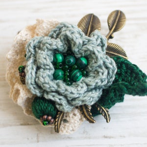 Textile brooch with crocheted green flower.