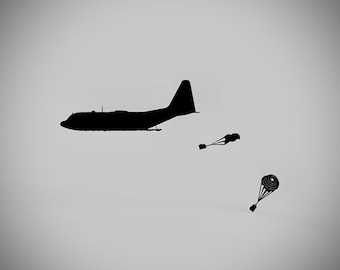 May include: A black silhouette of a military cargo plane dropping two parachutes from the air.