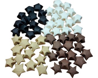 Könnte beinhalten: Eine Ansammlung zahlreicher kleiner, fünfzackiger Origami-Sterne, die in vier verschiedenen Farbgruppen angeordnet sind. Die Sterne sind aus Papier in den Farben Schwarz, Cremeweiß, Hellbraun und Dunkelbraun gefertigt und haben scharfe Faltkanten.
