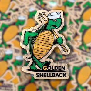 Peut inclure: Un autocollant représentant une tortue de dessin animé portant un chapeau de marin et tenant un trident. La tortue est verte avec une carapace jaune et le texte "Golden Shellback" est imprimé en dessous.