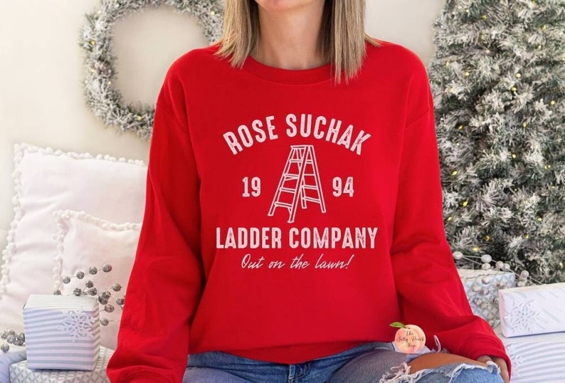 K&ouml;nnte beinhalten: Roter Pullover mit wei&szlig;em Text, der "ROSE SUCHAK 19 94 LADDER COMPANY Out on the lawn!" lautet. Zwischen den Jahren befindet sich eine wei&szlig;e Umrandung einer Leiter.