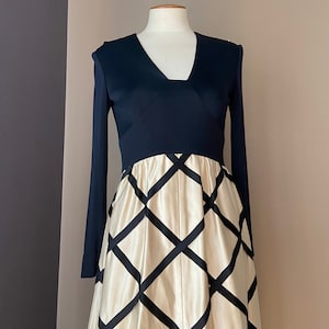 May include: A long-sleeved dress with a black bodice and a white skirt with black diamond-shaped patterns.