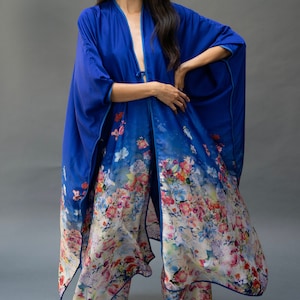 May include: A blue and floral print kimono with a long, flowing silhouette. The kimono has a tie closure at the waist and features a floral pattern with shades of pink, purple, and yellow.