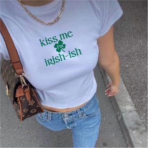 May include: White t-shirt with the text "Kiss me I'm Irish-ish" and a green shamrock graphic.