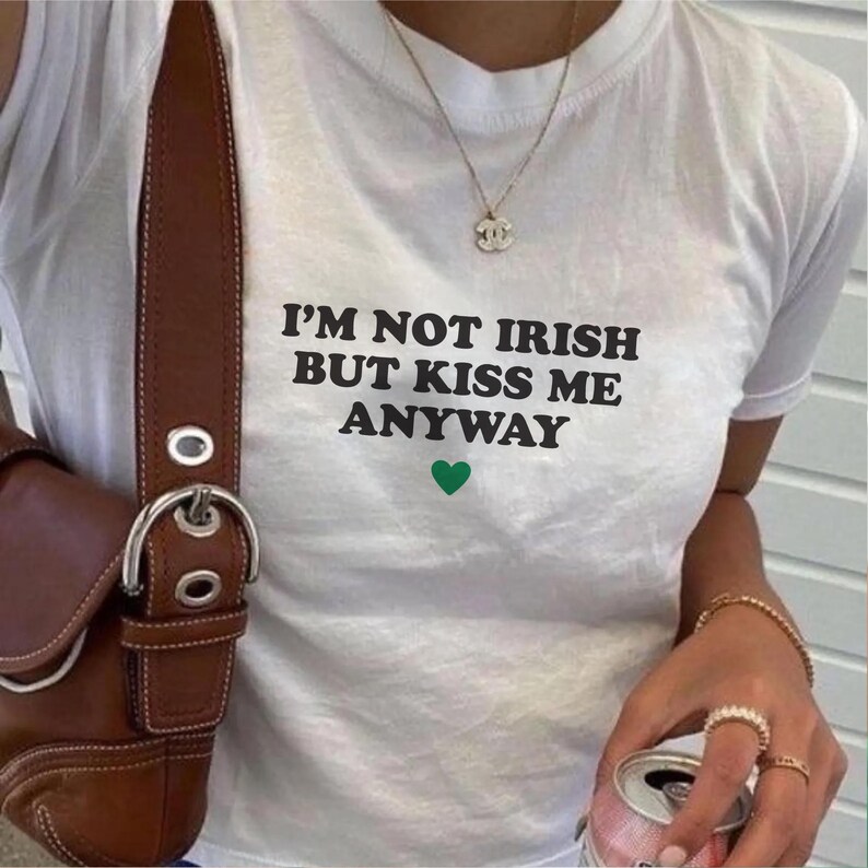 May include: White t-shirt with black text that reads "I'm not Irish but kiss me anyway" and a green heart.