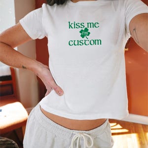 May include: White t-shirt with a green shamrock and the text "kiss me i'm custom".
