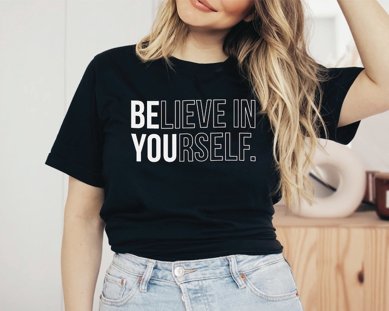May include: Black t-shirt with the white text "BELIEVE IN YOURSELF." The shirt has short sleeves and a crew neck. The text is in a bold, sans-serif font.