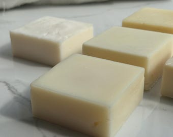 Könnte beinhalten: Vier Stück weiße Seife auf einer weißen Marmorfläche. Die Seifenstücke sind rechteckig und haben eine glatte, glänzende Oberfläche.