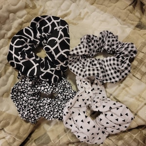 Puede incluir: Cuatro scrunchies con estampado en blanco y negro. Los scrunchies tienen diferentes patrones: geométrico, vichy, lunares y triángulos.