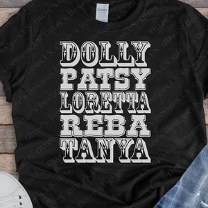 Op de afbeelding: Zwart T-shirt met witte tekst die "DOLLY PATSY LORETTA REBA TANYA" luidt.