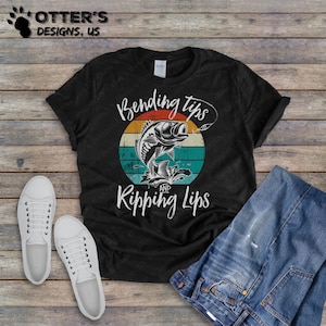 May include: Black t-shirt with a vintage-style graphic of a fish jumping out of the water. The graphic says "Bending Tips and Ripping Lips".