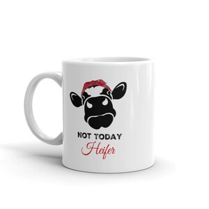 May include: White ceramic mug with a black and white illustration of a cow wearing a red bandana. The text "NOT TODAY Heifer" is printed below the cow.