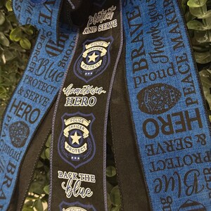 May include: Blue and black ribbon with the text "Protect and Serve", "Hometown Hero", "Back the Blue", "Brave", "Thank you", "Peace Makers", "Strong", "Protect and Serve", "Blue", "Hero" and a police officer badge.