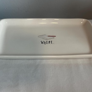 May include: White ceramic tray with a black and red illustration of a notebook and pencil. The text "WRITE." is printed below the illustration.