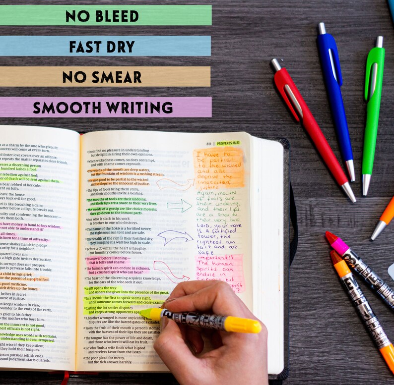 May include: A close-up of an open Bible with highlighted verses and handwritten notes. The text includes verses from Proverbs 16:21 and 18:10. A hand is holding a yellow highlighter pen over the text. Several colorful pens are visible on a wooden surface.