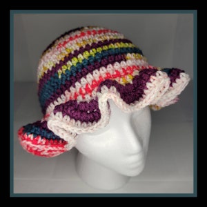 May include: A crocheted hat with a wide brim and a ruffled edge. The hat is made in a variety of colors, including pink, red, purple, teal, and yellow.