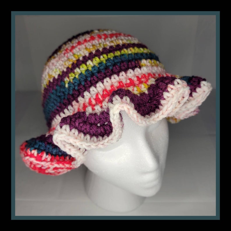May include: A crocheted hat with a wide brim and a ruffled edge. The hat is made in a variety of colors, including pink, red, purple, teal, and yellow.