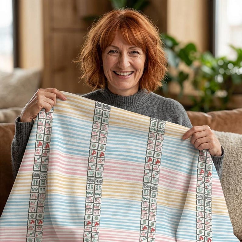 May include: A rectangular fabric throw blanket featuring a pattern of horizontal pastel stripes in light blue, yellow, and pink. The design is accented by vertical columns of repeating mahjong tile graphics in shades of green, red, and black.