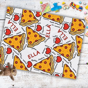May include: A white fabric with a repeating pattern of pizza slices, hearts, and the name "ELLA" in black lettering.