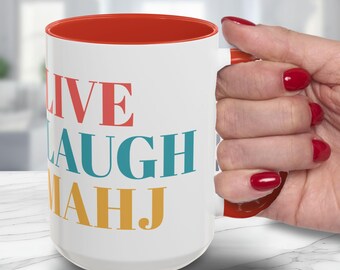 May include: A white ceramic mug with a bright orange interior and handle. The exterior features the text LIVE in red, LAUGH in teal, and MAHJ in yellow, all printed in a bold, serif font. The mug has a cylindrical shape and a smooth, glossy finish.