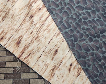 May include: Close-up of three different fabric swatches. The top swatch is a brown and green animal print fabric. The middle swatch is a light brown fabric with a wood grain pattern. The bottom swatch is a brown and beige brick pattern fabric.
