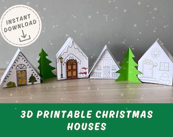 May include: A collection of 3D printable Christmas houses in white with various door and window designs. Some houses have snow-covered roofs and are decorated with a snowman, lights, and wreaths. Green paper Christmas trees are placed between the houses. The text "3D PRINTABLE CHRISTMAS HOUSES" is at the bottom.