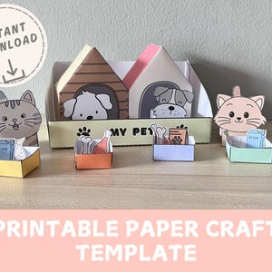 May include: A paper craft template featuring a cat and dog theme. The image shows a cat and two dogs in their houses, along with food and milk cartons. The words "Instant Download" and "Printable Paper Craft Template" are also visible.