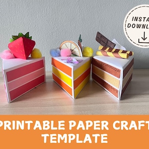 Könnte beinhalten: Drei Papierkuchenstücke mit verschiedenen Belägen: eine Erdbeere, eine Orangenscheibe und ein Schokoriegel. Die Kuchen sind rot, orange und braun mit verschiedenen farbigen Schichten. Der Text "PRINTABLE PAPER CRAFT TEMPLATE" und "INSTANT DOWNLOAD" ist enthalten.