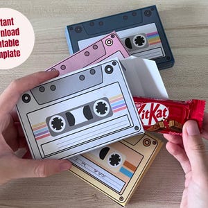 Puede incluir: Cajas de regalo con forma de cinta de cassette en gris, rosa y amarillo, con una barra de chocolate Kit Kat. Las cajas tienen un diseño retro con rayas coloridas y el texto "Instant Download Printable Template".